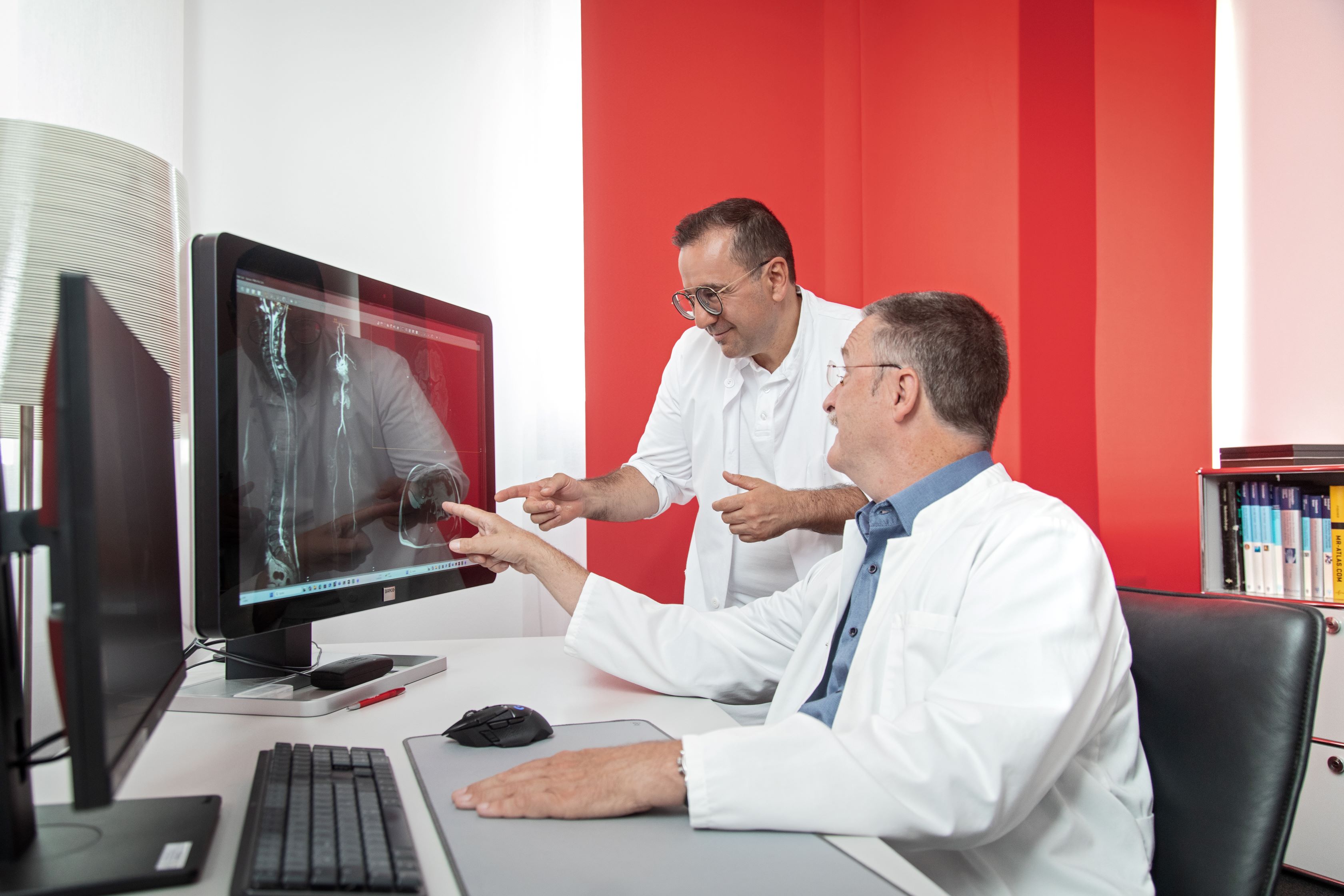 Zwei Ärzte, die sich über die Bilder einer Ganzkörper-MRT-Untersuchung unterhalten